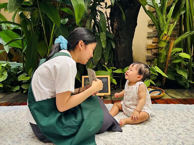 Cô giáo MeSchool đang dạy một bé nhỏ trong không gian cây xanh — minh hoạ tinh thần giáo dục chuyển hoá